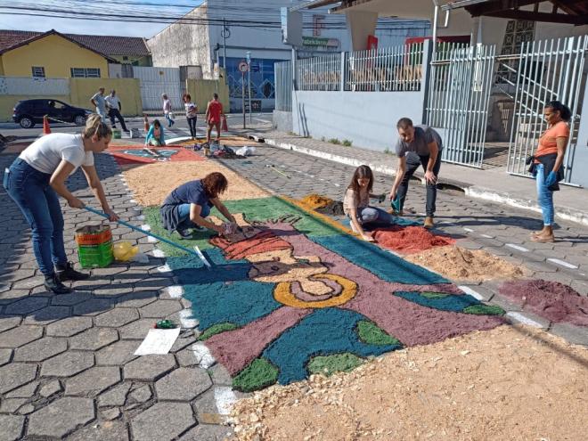 Fiéis ajudam a confeccionar os tapetes do Corpus Christi no centro de Coronel Fabriciano.