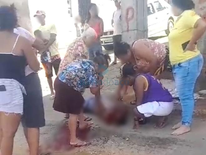 A vítima ferida é amparada por populares e familiares na tarde desta sexta-feira