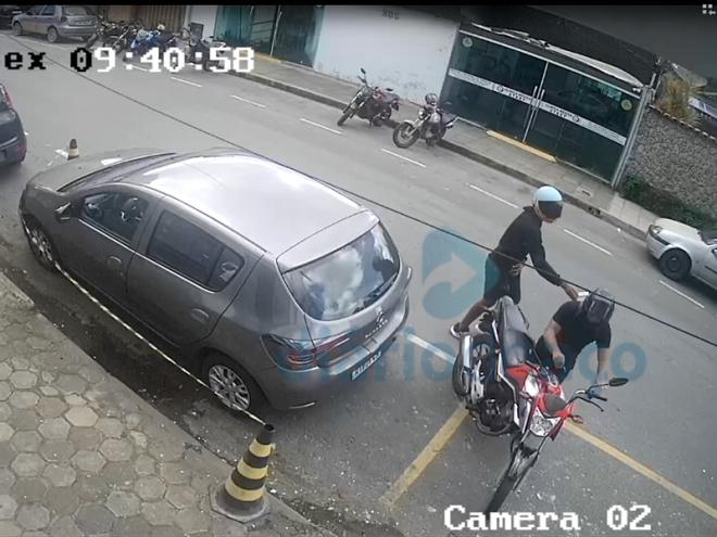 O momento que os dois marginais fogem em uma motocicleta com os produtos roubados