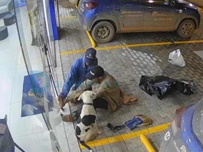O momento que os dois autores, acompanhado de um cachorro, estouram a porta de vidro da loja