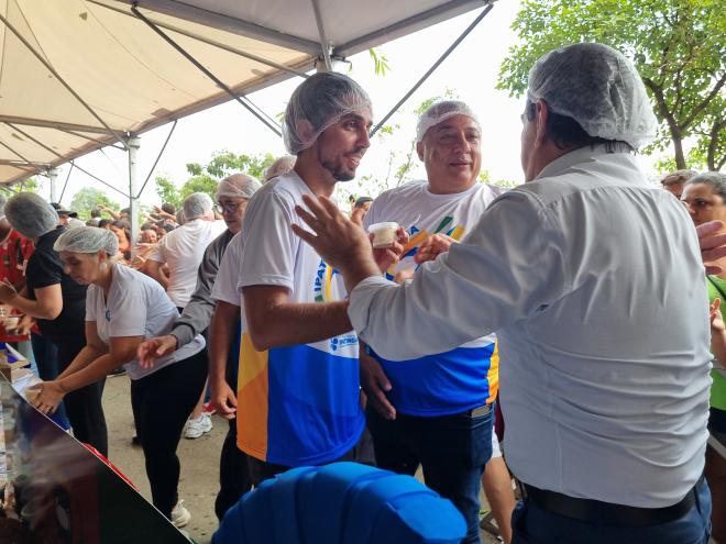 Prefeito Gustavo Nunes, ao lado do vereador Adiel Oliveira e do deputado federal Domingos Sávio entregando os potes de bolo à comunidade