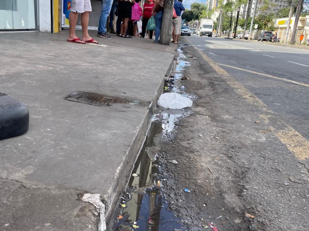 Ao lado da rede de esgoto há uma lanchonete, uma sorveteria e um ponto de ônibus