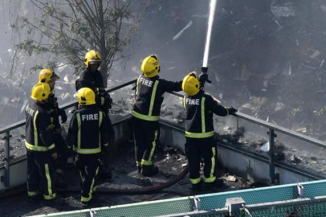 Homens do Corpo de Bombeiros combatem o incêndio de grandes proporções em um edifício de 24 andares em Londres