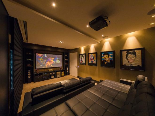 Cinema em casa: Grandes ícones do cinema estampam as paredes desse home theater projetado pela arquiteta Andréa Benthien. Na hora de dar o play, o isolamento acústico e de incidência de luz externa trazem a sensação de cinema ao espaço, enquanto os sofás garantem todo o conforto de estar em casa