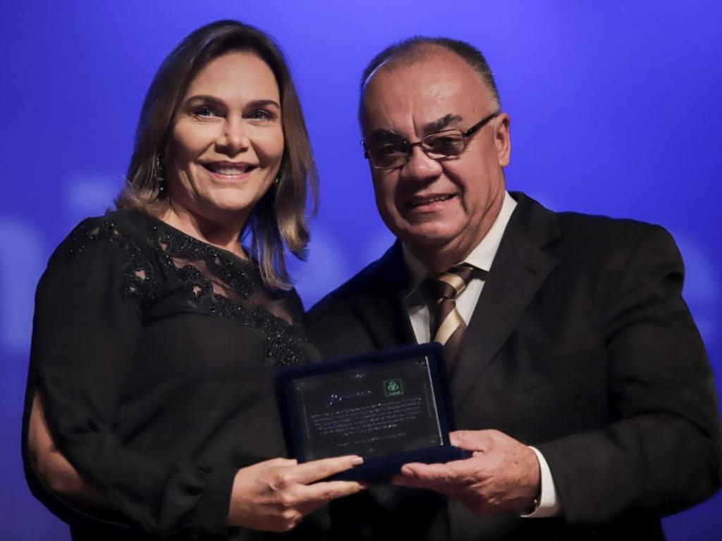 Rietor Genésio Zeferino entrega placa de homenagem à Coordenadora de Comunicação Corporativa e Relações Institucionais da Cenibra, Leida Hermsdorff Horst Gomes.