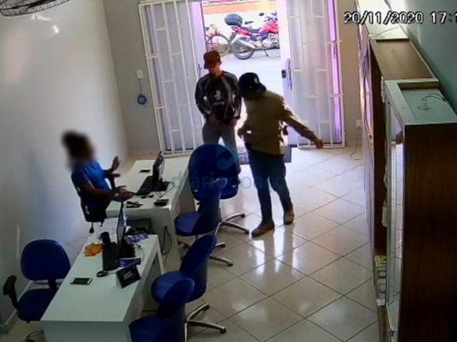 O momento que os assaltantes rendem uma das funcionárias na loja