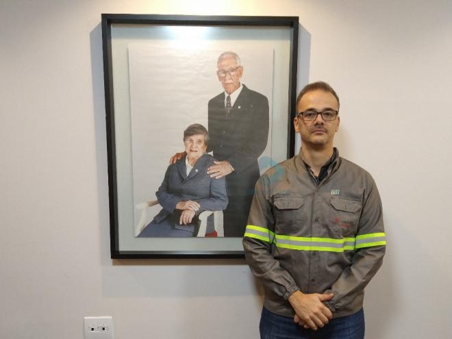 Edilar Luciano Vitali Alves ao lado da fotografia dos fundadores da Cipalam: Raimundo Anício e Ita Drumond