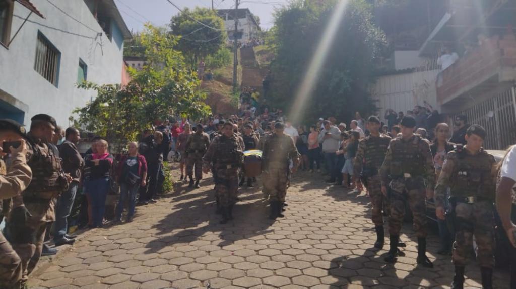 Familiares e colegas de farda carregam o corpo do policial para o sepultamento no fim da manhã deste sábado 