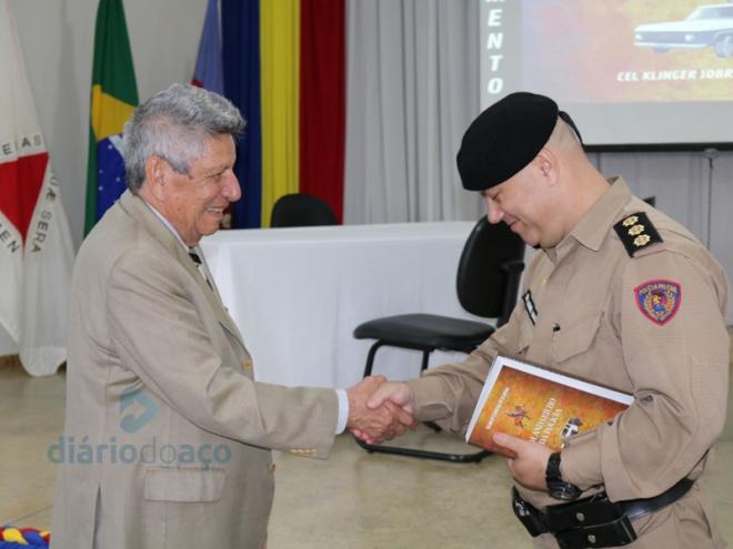Coronel Klinger entrega um exemplar para o coronel Lemos Dias, comandante da 12ª Região da PM